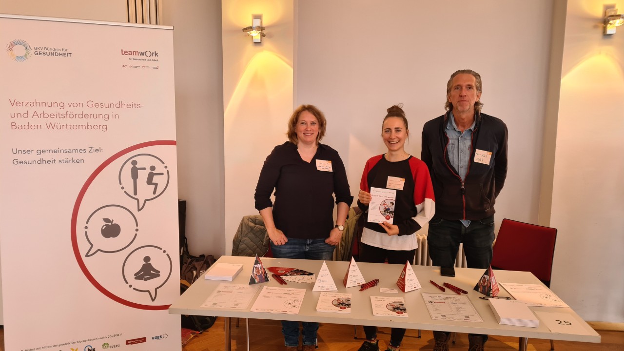 Teamwork für Gesundheit und Arbeit am 8.10.24, 2 Frauen und ein Mann vor Roll-up stehend Teamwork für Gesundheit und Arbeit am 8.10.24, 2 Frauen und ein Mann vor Roll-up stehend