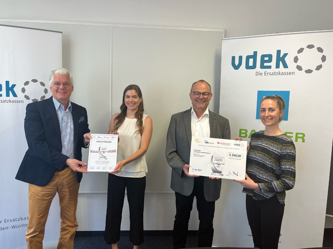 Förderpreis "Gesunde Kommune" 2 Frauen und 2 Männer mit Auszeichnung stehend Förderpreis "Gesunde Kommune" 2 Frauen und 2 Männer mit Auszeichnung stehend