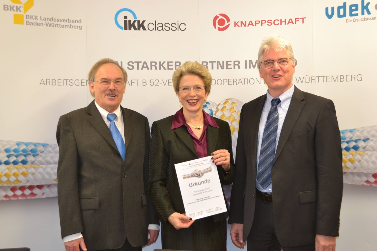 Hugo Schüle, Barbara Bosch und Frank Winkler stehen vor einem Banner der B 52-Verbändekooperation, Barbara Bosch hält eine Urkunde des Förderpreises 2013 in den Händen
