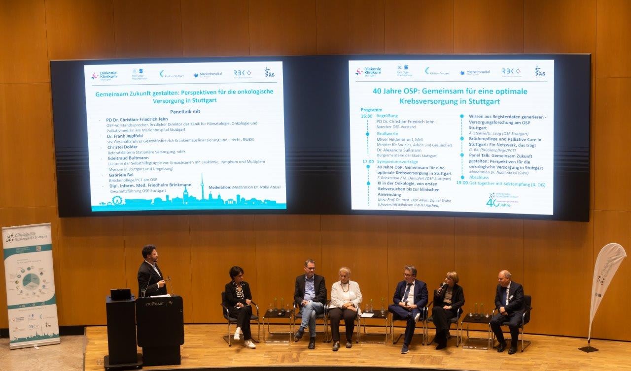 40 Jahre OSP Stuttgart, 1 Mann stehend, 3 Frauen und 3 Männer in der Diskussion sitzend 