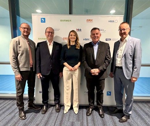 Gesundheitsministerin Gerlach, die Spitzen der bayerischen Ersatzkassen und Thomas Hackenberg stehend vor einem Roll-Up