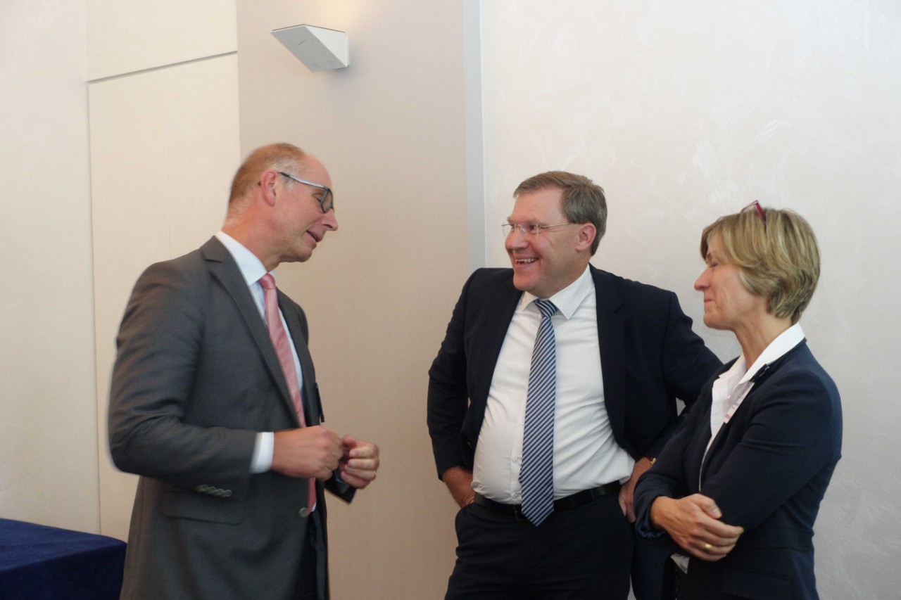 Zwei M&auml;nner und eine Frau unterhalten sich im Stehen.