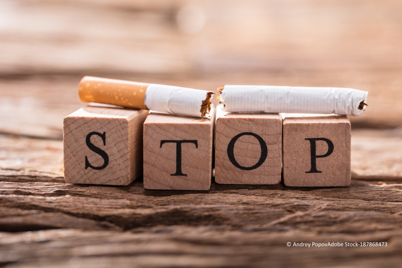 Durchgebrochene Zigarette liegt auf Würfen, auf welchen "STOP" steht