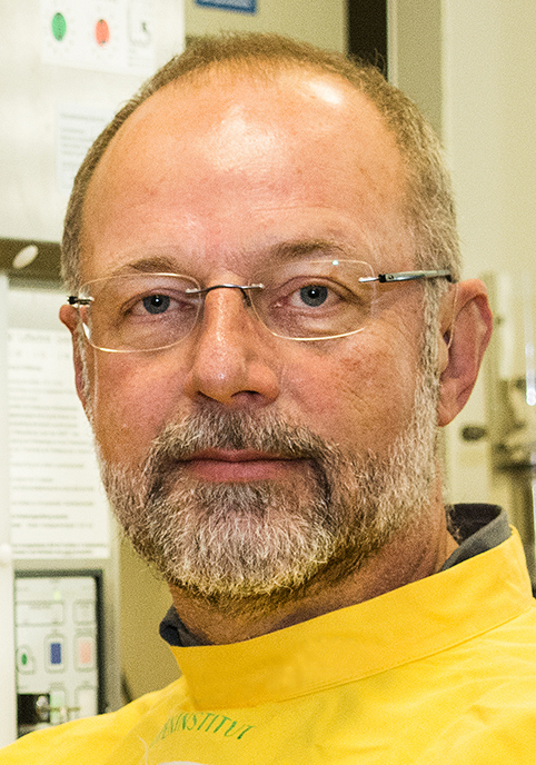 Mann mit Bart und Brille in gelbem Laborkittel