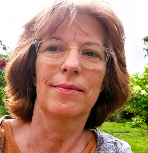 Frau mit großer Brille vor grünem Garten