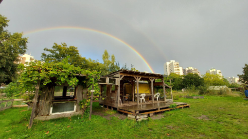 Blick auf eine Gartenhütte unter einem Regenbogen