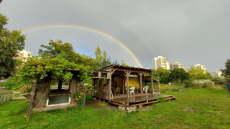 Blick auf eine Gartenhütte unter einem Regenbogen