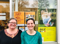 Zwei Frauen vor einer Glasfront mit Plakaten