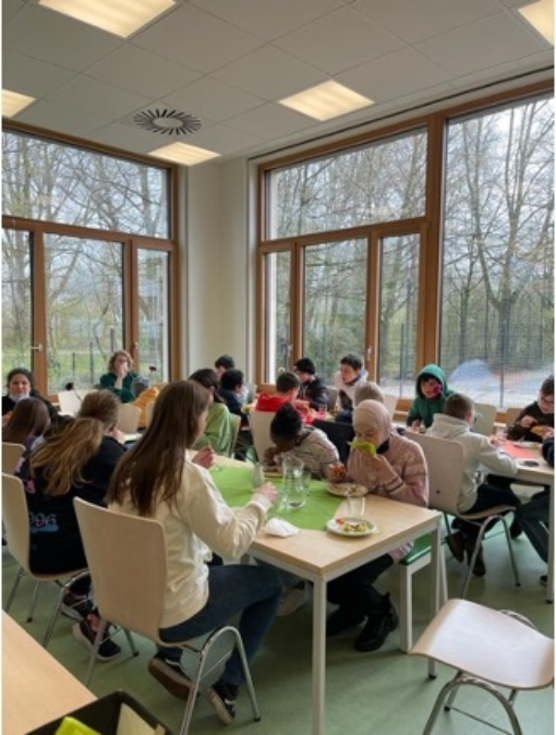 Kinder sitzen beim Mittagessen an langen Tischen