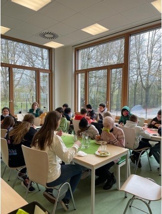 Kinder sitzen beim Mittagessen an langen Tischen