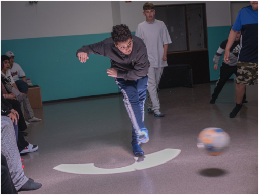 Ein Junge tritt einen Ball weg, andere schauen zu