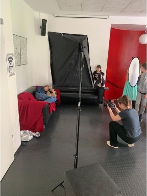Ein Mädchen liegt auf einem Sofa, eine Frau mit Kamera nimmt die Szene auf