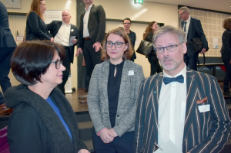 Zwei Frauen im Blazer und ein Mann mit Fliege