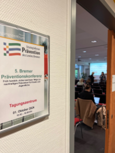 Blick durch eine geöffnete Tür in einen Raum mit Menschen