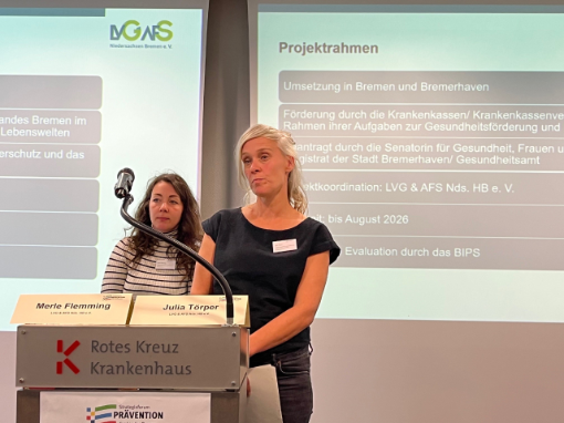 Zwei Frauen am Pult, im Hintergrund Präsentation Zwei Frauen am Pult, im Hintergrund Präsentation