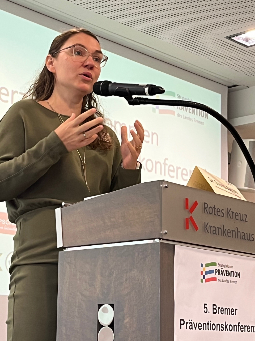 Eine Frau am Pult, im Hintergrund Präsentation Eine Frau am Pult, im Hintergrund Präsentation