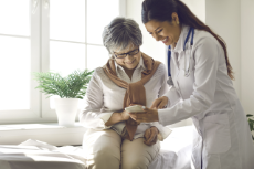 Mature lady sitting on exam bed learning to download health tracker for senior citizens Mature lady sitting on exam bed learning to download health tracker for senior citizens
