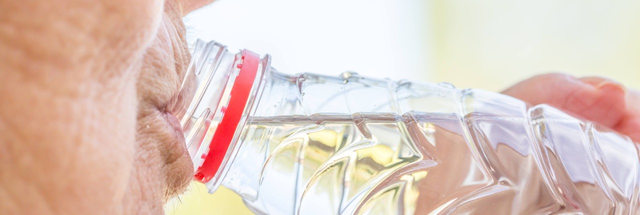 Ältere Frau trinkt aus Wasserflasche - Ausschnitt