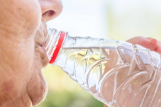 Ältere Frau trinkt aus Wasserflasche