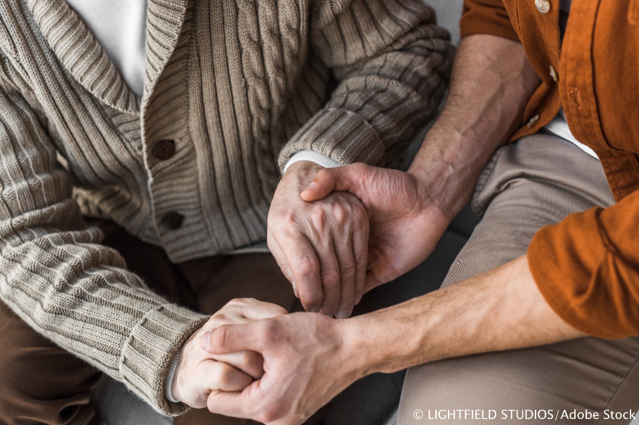 Senior und Pflegekraft halten sich an den Händen