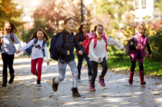 Kinder mit Schultasche rennen