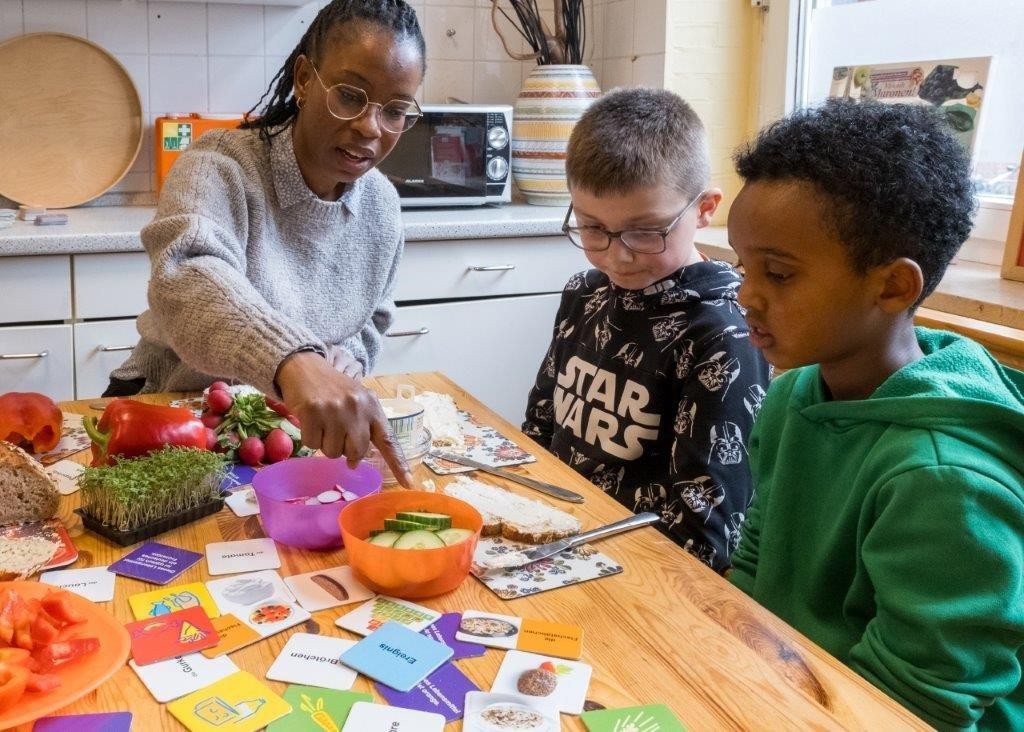 Eine Schulgesundheitsfachkraft an der Grundschule Speckenreye in Hamburg bereitet mit Schülern gesunde Pausenbrote zu