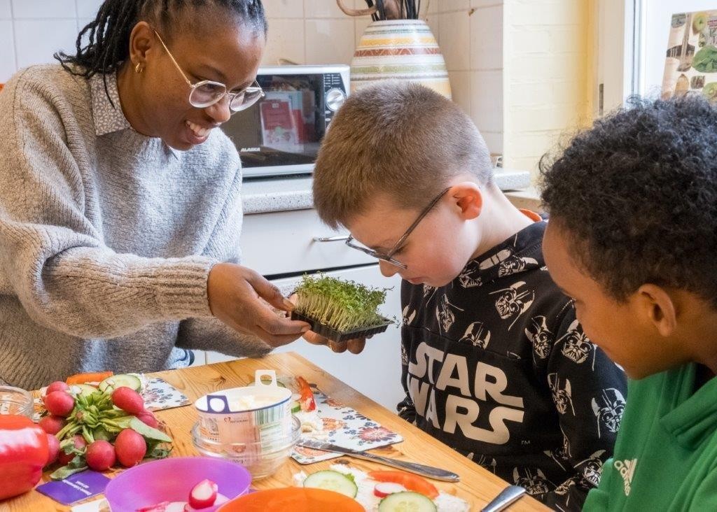 Eine Schulgesundheitsfachkraft an der Grundschule Speckenreye in Hamburg bereitet mit zwei Schülern gesunde Pausenbrote zu Eine Schulgesundheitsfachkraft an der Grundschule Speckenreye in Hamburg bereitet mit zwei Schülern gesunde Pausenbrote zu