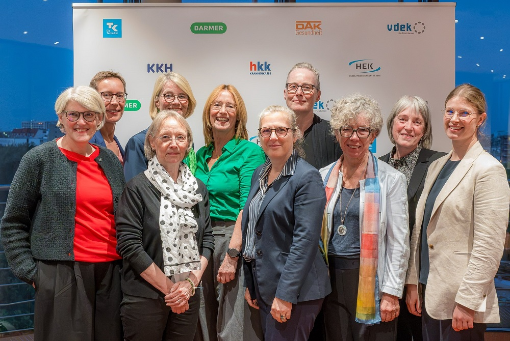 Zehn Frauen stehen vor Banner mit Logos