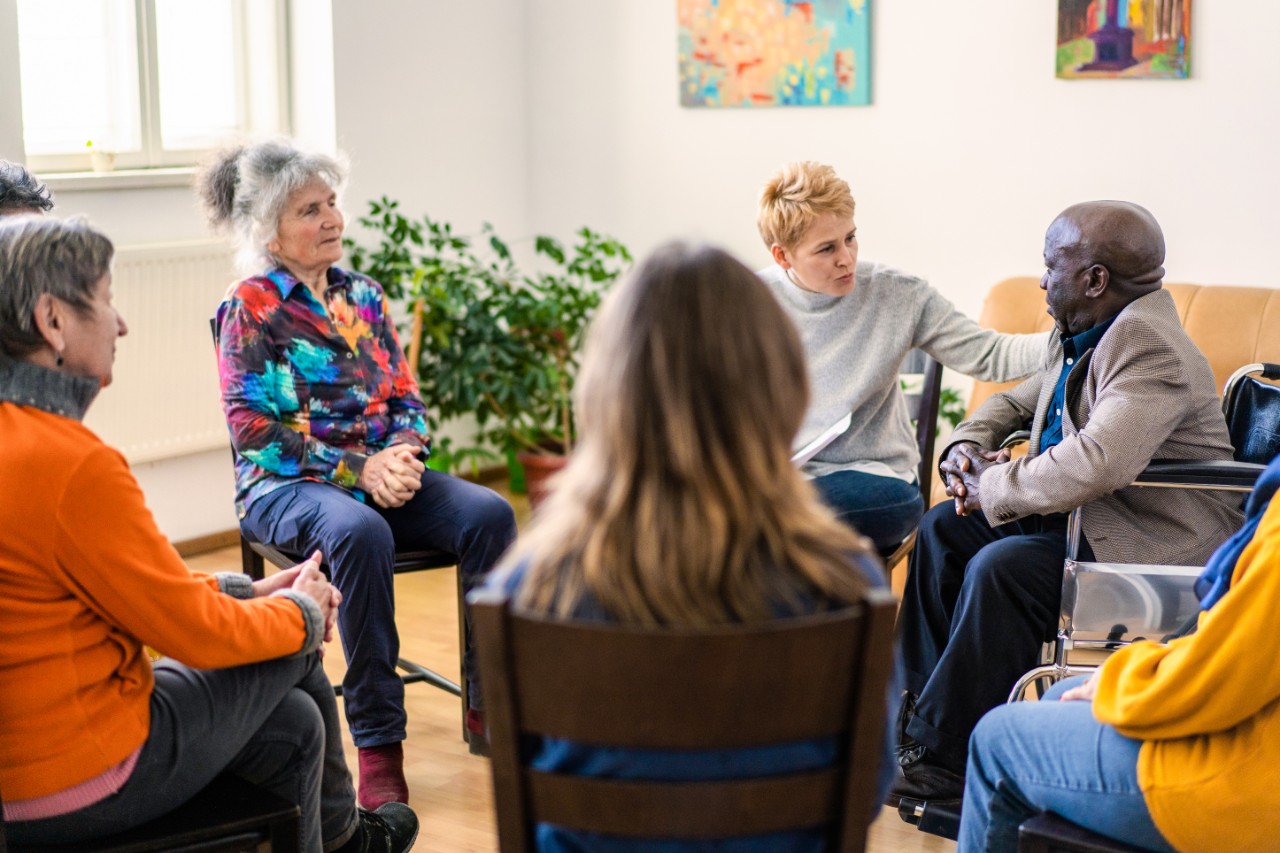 Bei einer Gruppentherapie-Sitzung wendet sich die Therapeutin einem Patienten zu