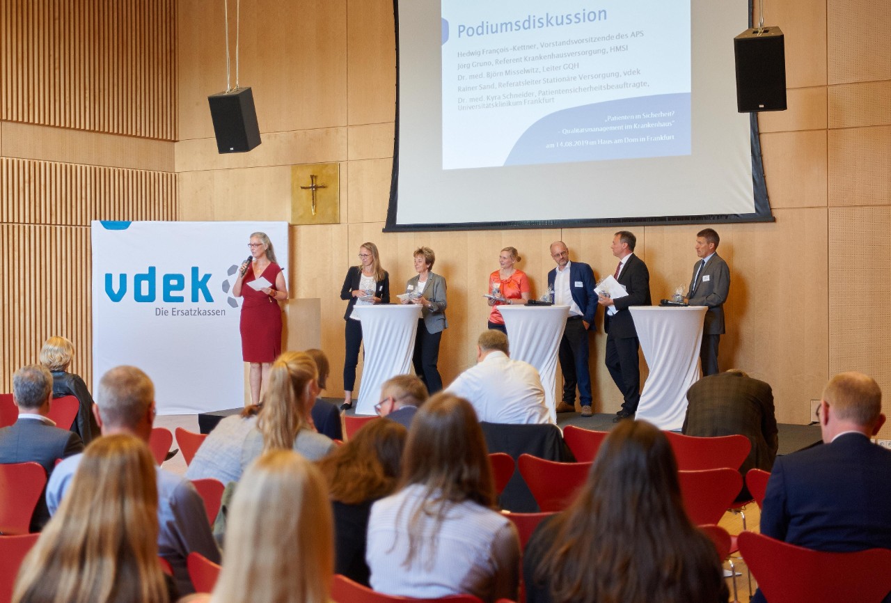 vier Frauen und drei Männer stehen bei einer Podiumsdiskussion vor Publikum vier Frauen und drei Männer stehen bei einer Podiumsdiskussion vor Publikum