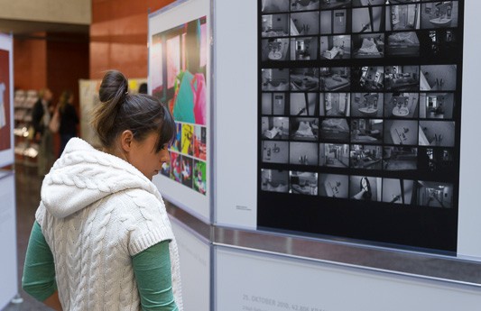 Eine Besucherin der Ausstellung schaut sich ausgestellte Bilder an