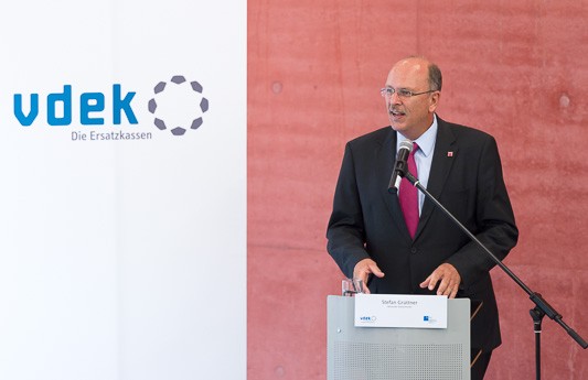 Sozialminister Stefan Gr&uuml;ttner steht am Rednerpult und spricht, links von ihm steht ein vdek-Banner