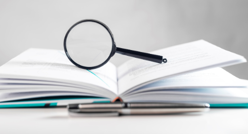 Lupe auf aufgeschlagenem Buch_valiantsin suprunovichiStockgetty images plus