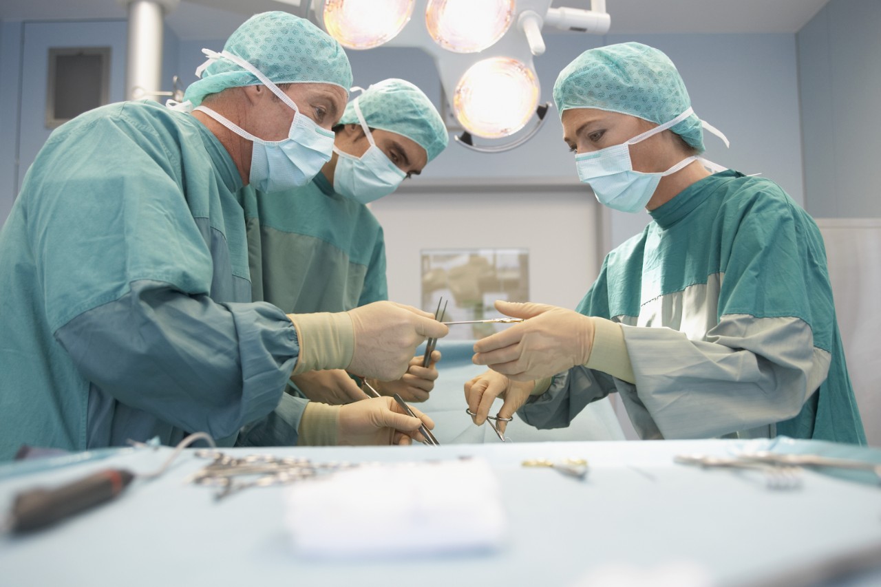 Three Surgeons At Work In Operating Theatre Three Surgeons At Work In Operating Theatre
