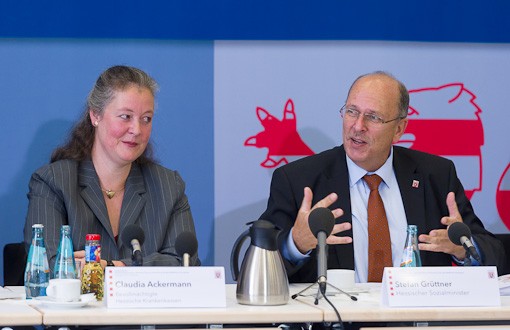 Claudia Ackermann und Stefan Gr&uuml;ttner sitzen am Podium, Herr Gr&uuml;ttner gestikuliert und spricht