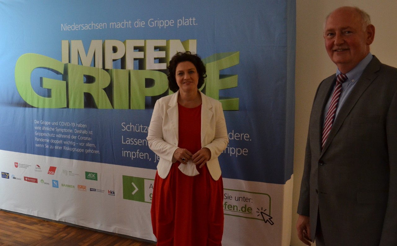 Frau und Mann stehen vor einem Aufsteller mit dem Slogan "Niedersachsen macht die Grippe platt." Frau und Mann stehen vor einem Aufsteller mit dem Slogan "Niedersachsen macht die Grippe platt."