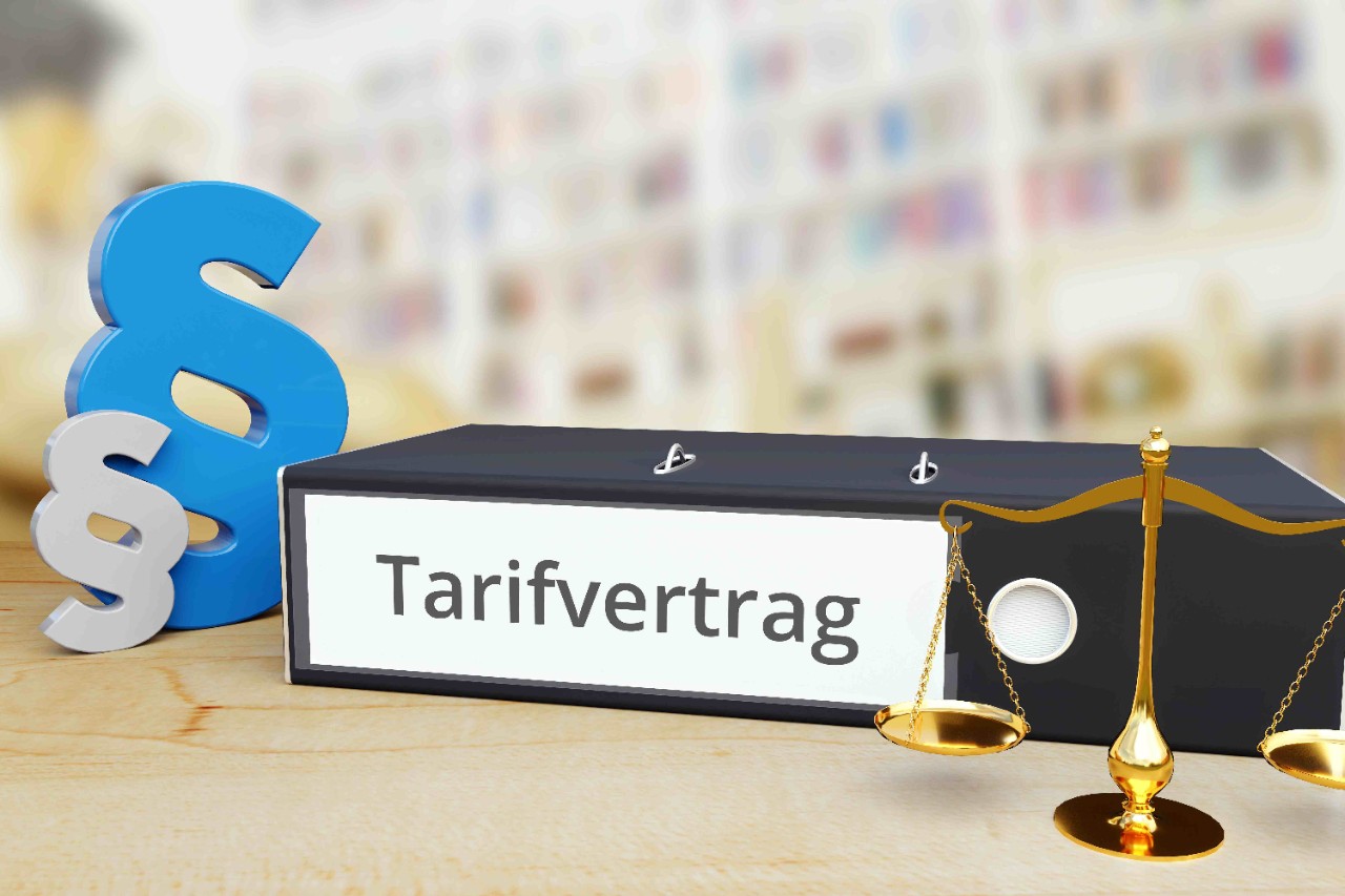 Aktenordner mit der Aufschrift Tarifvertrag, daneben Paragraphen-Zeichen und Waage