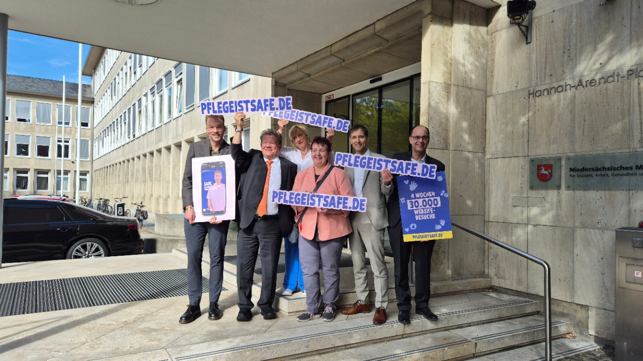 Eine Gruppe Menschen h&auml;lt Schilder zur Pflegekampagne in die Luft