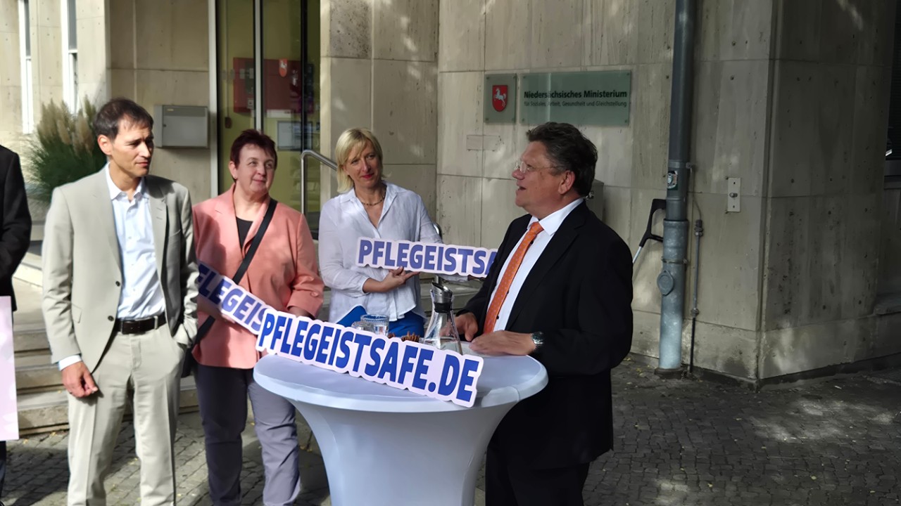 Ein Mann spricht an einem runden Tisch, andere hören zu