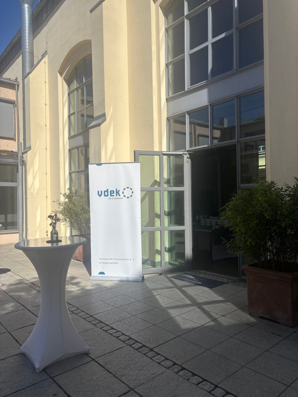 Ein wei&szlig;er Auftseller mit vdek-Logo vor einem Eingang