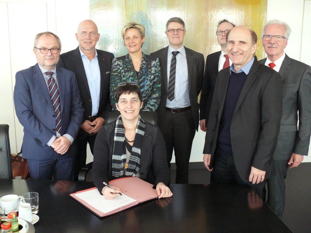 Gesundheitsministerin Barbara Steffens unterschreibt einen Vertrag - im Hintergrund 7 weitere Personen