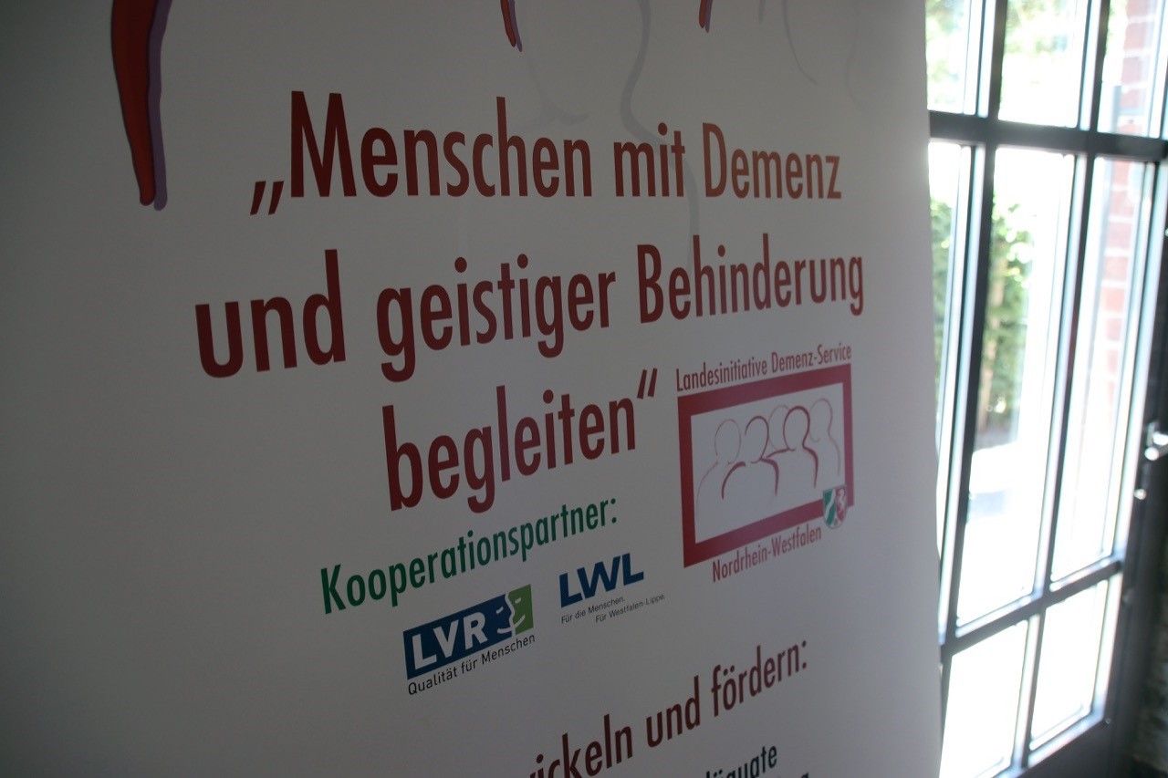 Schild mit Titel der Veranstaltung Menschen mit Demenz und geistiger Behinderung begleiten