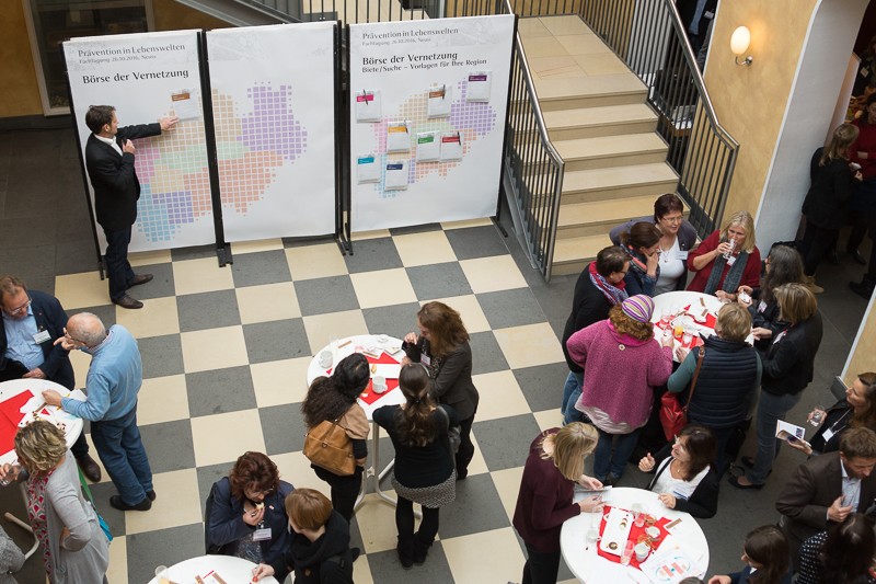 Blick von der ersten Etage ins Foyer mit Besuchern an Stehtischen