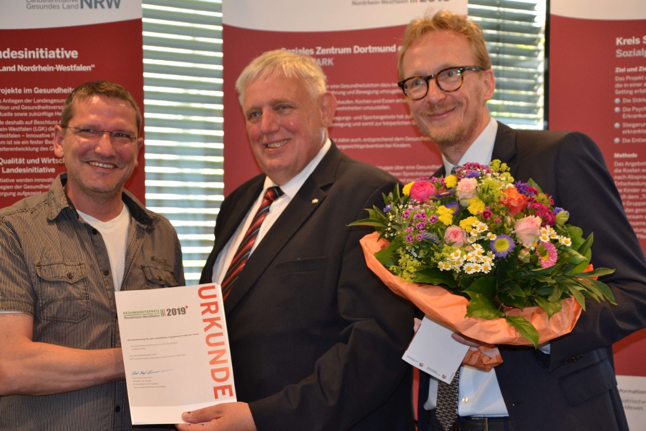 NRW Gesundheitsminister Laumann (mitte) &uuml;berreicht den Preis an Thorsten Szelies  (li, Soziales Zentrum Dortmund) und Dirk Ruiss (re, vdek NRW)
