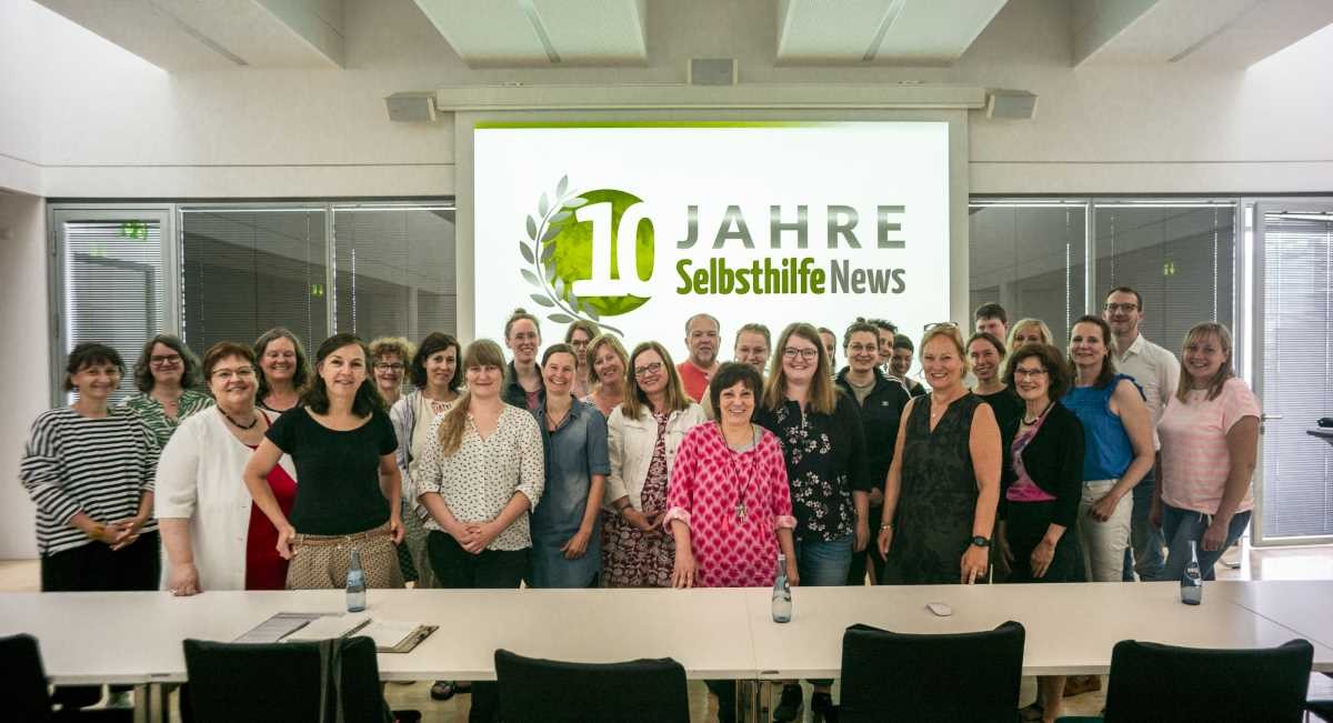 Gruppe vor dem Jubiläumsbanner 10 Jahre SelbsthilfeNews Gruppe vor dem Jubiläumsbanner 10 Jahre SelbsthilfeNews