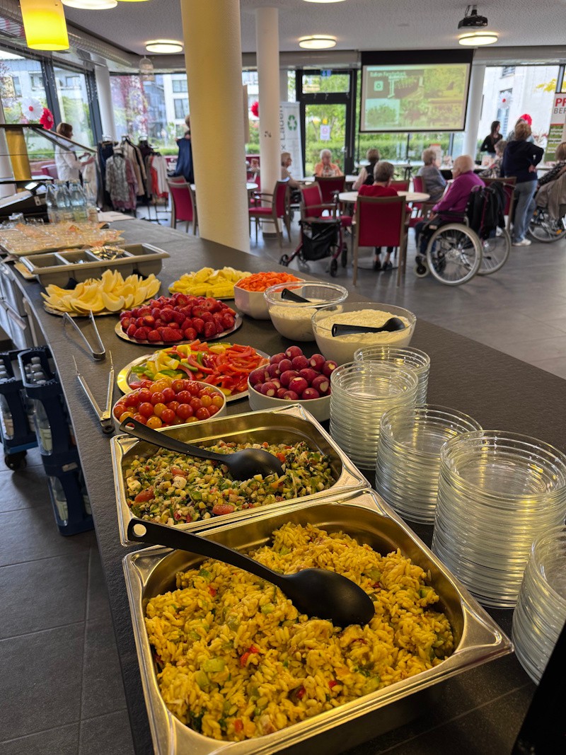 Aufgebautes B&uuml;ffet mit verschiedenem gesundem Essen, im Hintergrund einige Menschen sitzend