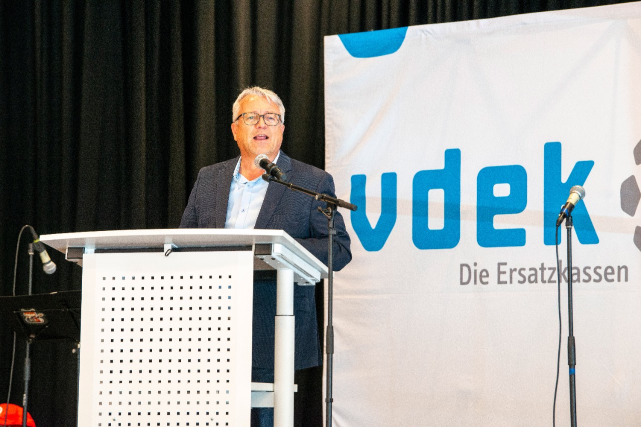 Herr Schneider ist auf dem Podium und begr&uuml;&szlig;t die Teilnehmer der Veranstaltung