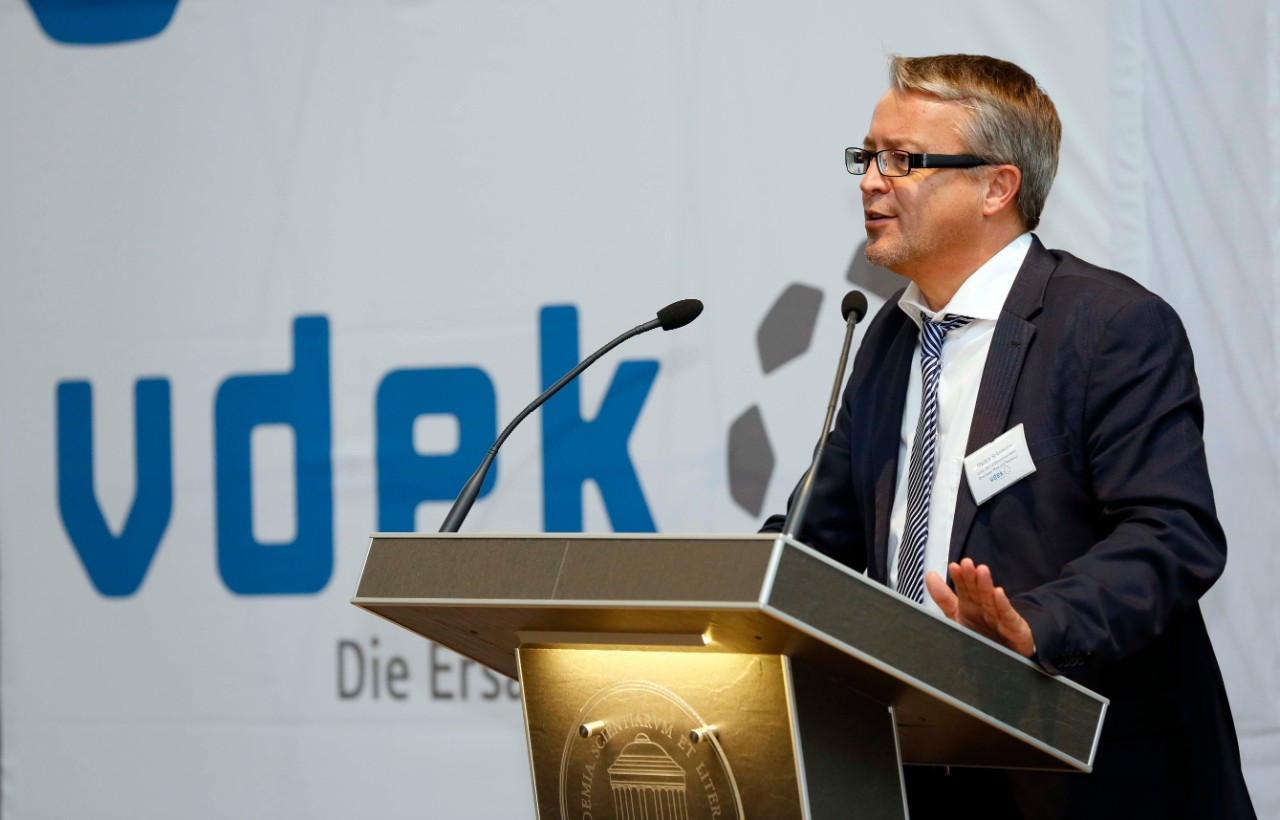 vdek-Leiter Martin Schneider steht am Rednerpult und spricht, links von ihm zu sehen ist das vdek-Logo