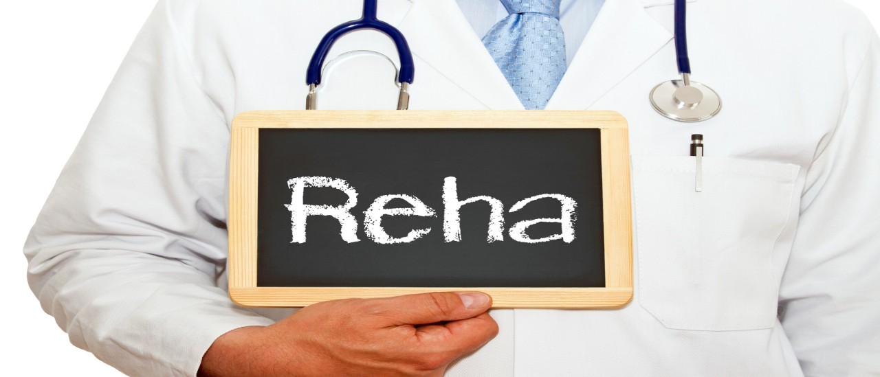 Symbolbild: Mediziner hält ein Schild mit der Aufschrift "Reha" in der HandSy
