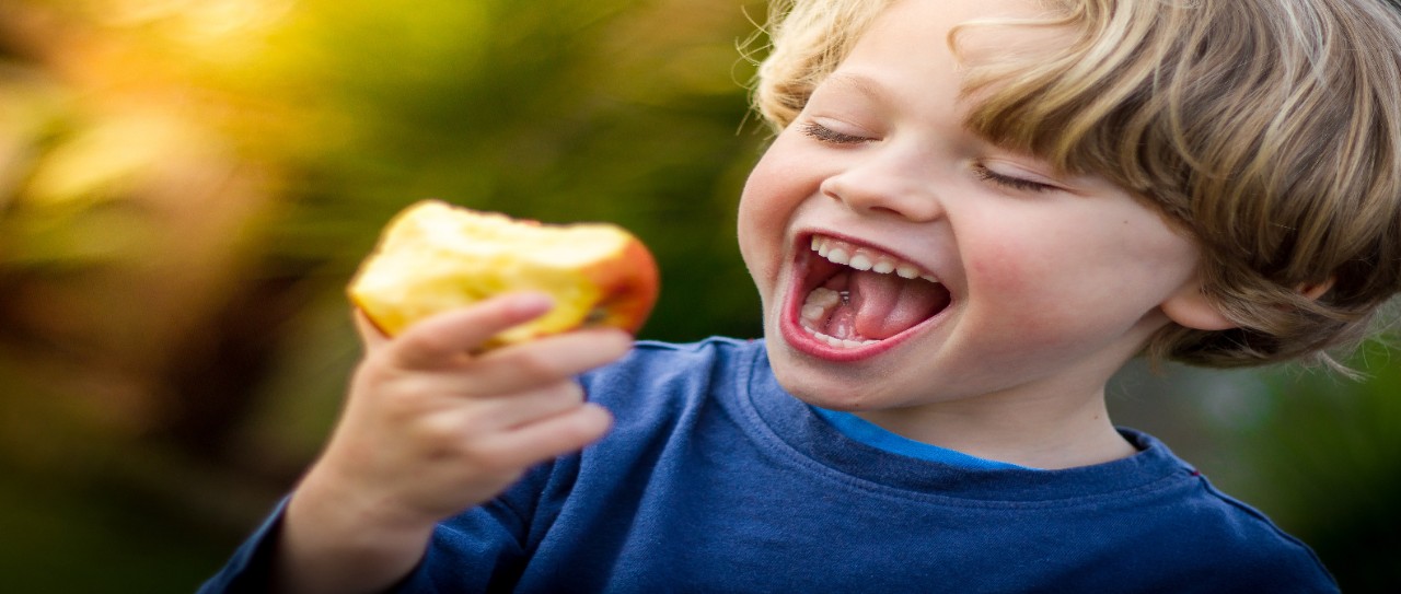 cute blonde child about to take a bite of an apple